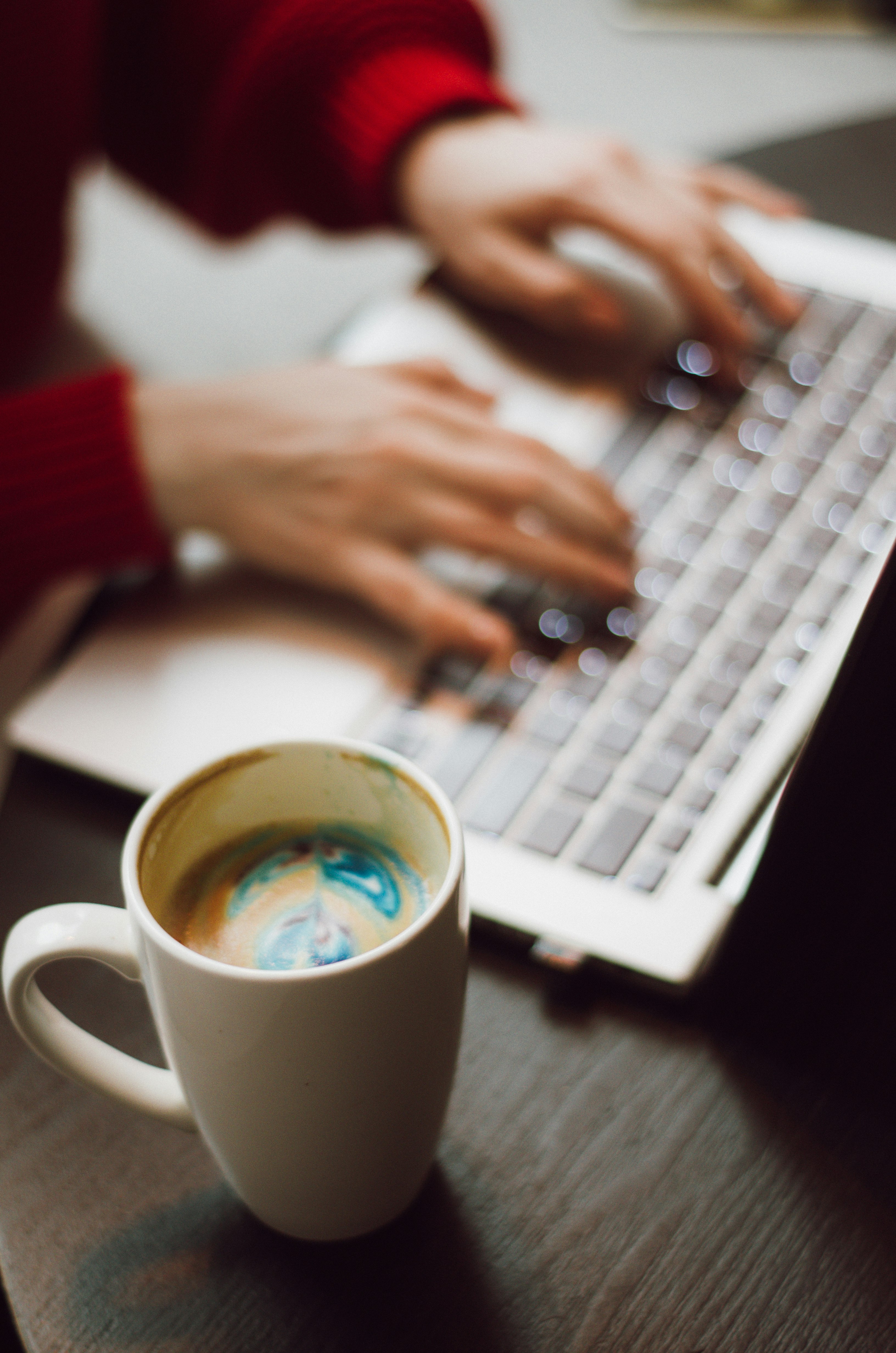 person holding white ceramic mug on white and black laptop computer